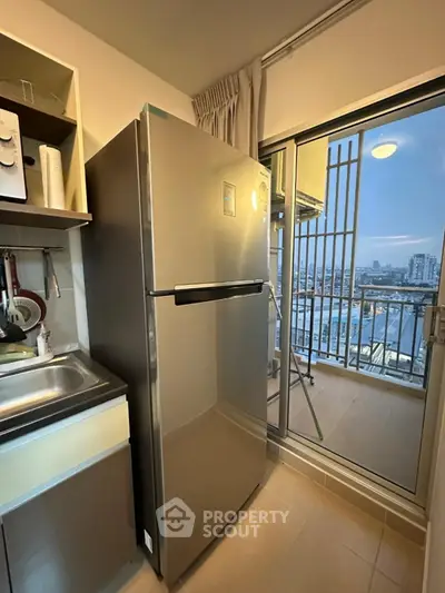 Modern kitchen with stainless steel fridge and balcony view in high-rise apartment