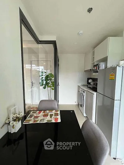 Modern kitchen with dining area, featuring a washing machine and sleek appliances.