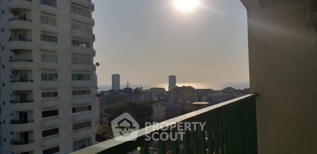 Stunning high-rise balcony view overlooking cityscape and ocean horizon at sunset.