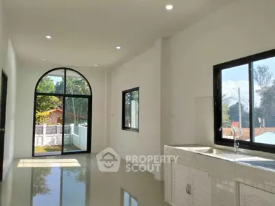 Bright and spacious living area with large windows and modern kitchen setup.