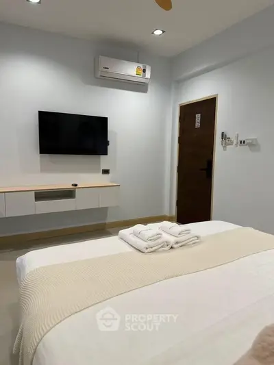 Modern bedroom with wall-mounted TV and air conditioning unit.