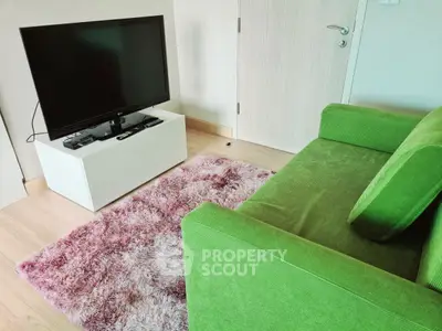 Cozy living room with green sofa and modern TV setup on plush rug