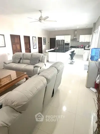 Spacious open-layout living room with modern kitchen and cozy seating area, perfect for family gatherings.