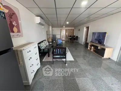 Spacious living room with modern decor and large TV, ideal for family gatherings.