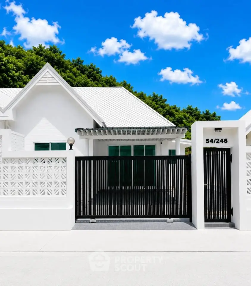Charming white house with modern gate and lush greenery, perfect for serene living.