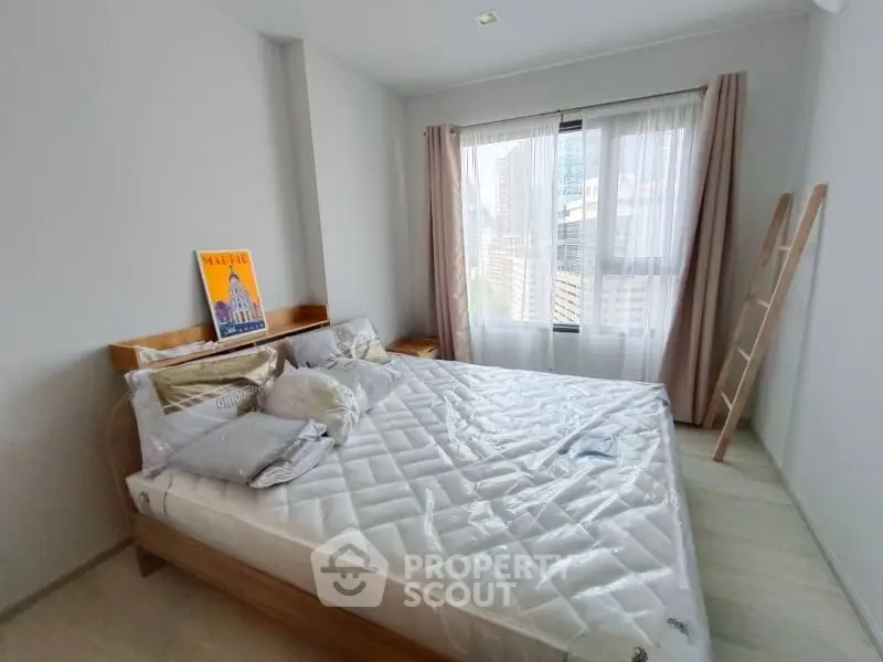 Bright and cozy bedroom with large window and modern decor in urban apartment.