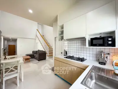 Modern open-plan kitchen and living area with sleek design and staircase.