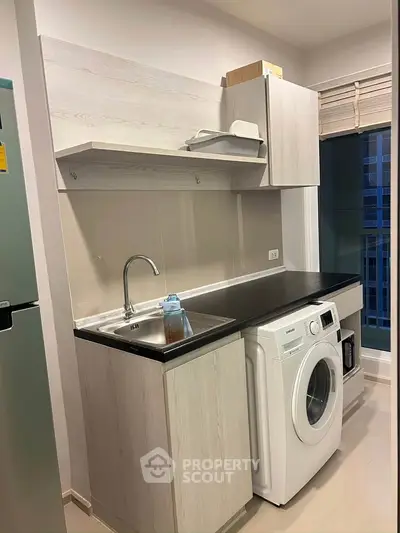 Modern kitchen with washing machine and sleek cabinetry in a compact space.