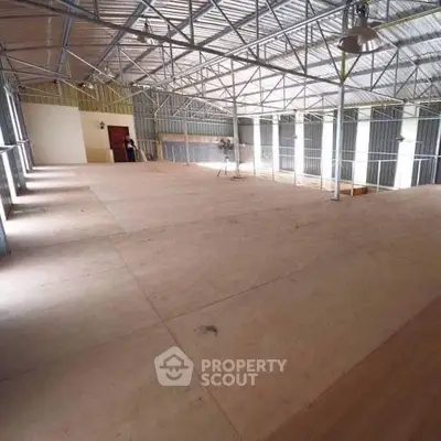 Spacious industrial warehouse interior with high ceilings and ample natural light.