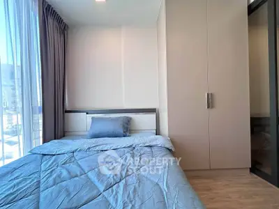 Modern bedroom with large window and stylish decor in a high-rise apartment.