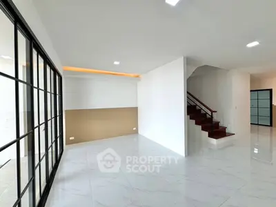 Spacious modern living room with elegant staircase and large windows