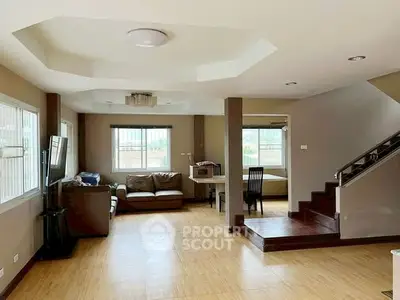 Spacious living room with modern design and ample natural light, featuring wooden flooring and stylish ceiling.