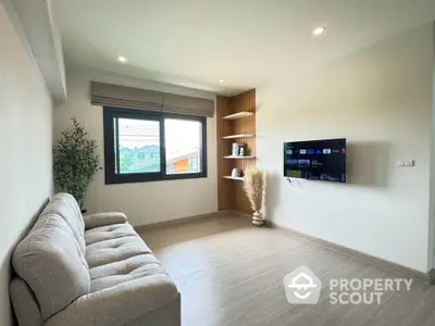 Modern living room with cozy sofa and wall-mounted TV, featuring large window and stylish decor.