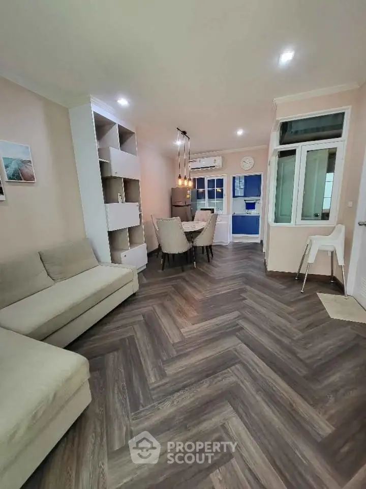 Modern living room with elegant herringbone flooring and cozy dining area