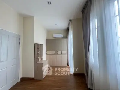 Spacious bedroom with wooden flooring and large windows for natural light.