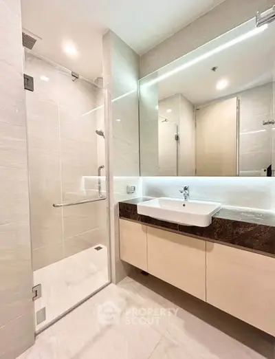 Modern bathroom with sleek design, featuring a glass shower enclosure and elegant vanity.