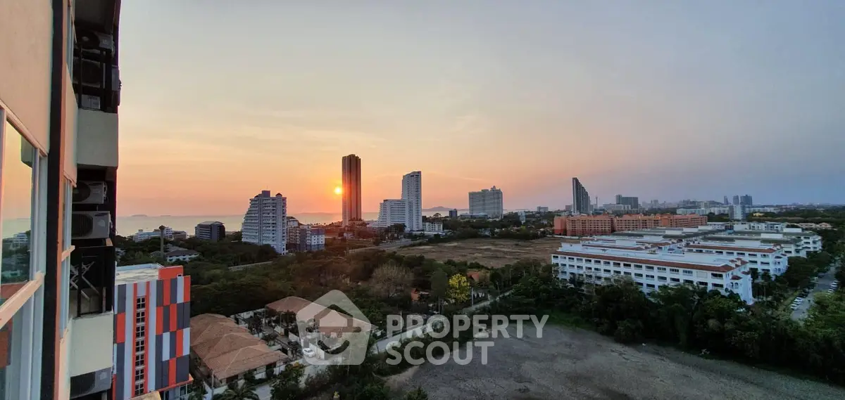Stunning sunset view from high-rise apartment overlooking city skyline and ocean.