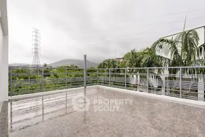 Spacious balcony with scenic view of lush greenery and mountains, perfect for relaxation.