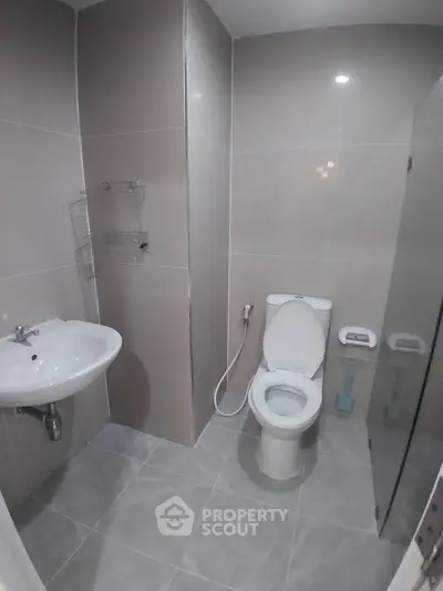 Modern bathroom with sleek tiles and essential fixtures in a contemporary apartment.
