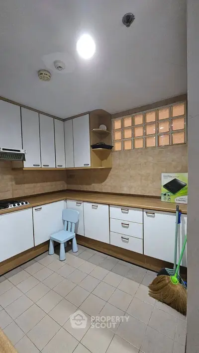 Spacious kitchen with modern cabinetry and tiled flooring, featuring a cozy corner for dining.