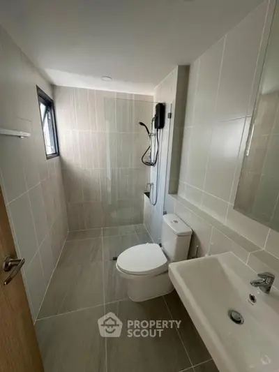 Modern bathroom with sleek design, featuring a shower, toilet, and sink in a neutral color palette.