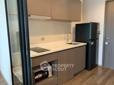 Modern compact kitchen with sleek cabinetry and appliances in a stylish apartment.