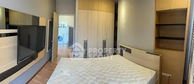 Modern bedroom with built-in storage and wall-mounted TV, featuring a glimpse of laundry area.