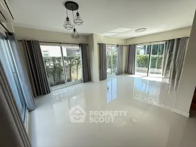 Spacious living room with large windows and garden view, perfect for natural light lovers.