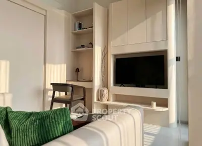 Modern living room with built-in TV unit and cozy seating area, featuring elegant decor and natural light.