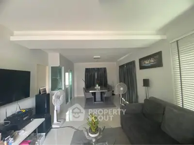 Spacious living room with modern decor and dining area, featuring sleek furniture and ample natural light.