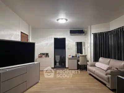 Spacious living room with modern decor and sleek furniture, featuring a large TV and comfortable seating.