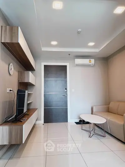 Modern living room with sleek furniture and wall-mounted TV in a stylish apartment.