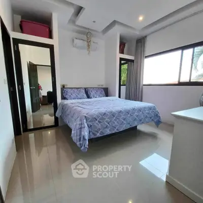 Spacious bedroom with modern decor and large window for natural light.