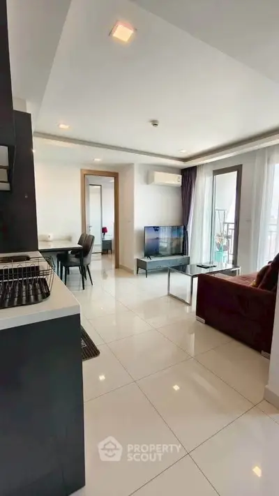 Modern open-plan living room with sleek kitchen and balcony access in a stylish apartment.