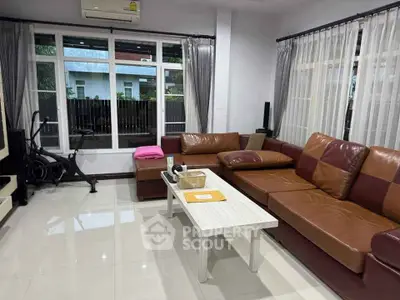 Spacious living room with modern leather sofa and large windows for natural light.