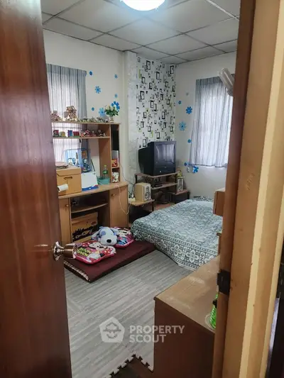Cozy bedroom with TV, desk, and floor mattress in a compact space.
