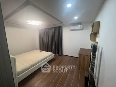 Modern minimalist bedroom with wooden flooring and sleek furniture