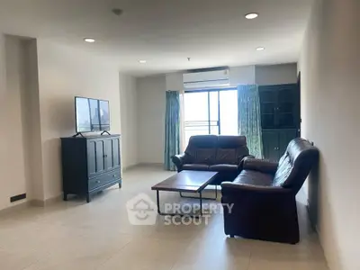 Spacious living room with modern furniture and natural light, perfect for relaxation.