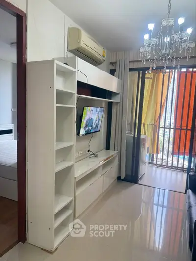 Modern living room with TV, air conditioning, and balcony access in stylish apartment.