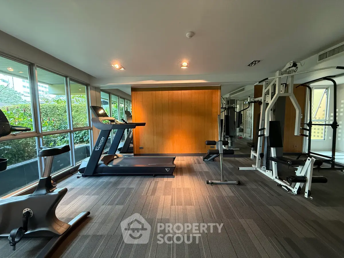 Modern gym with state-of-the-art equipment and large windows offering a lush garden view.