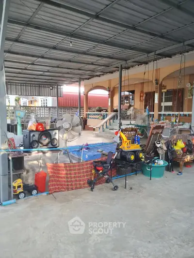 Spacious covered outdoor area with toys and household items, ideal for family gatherings.