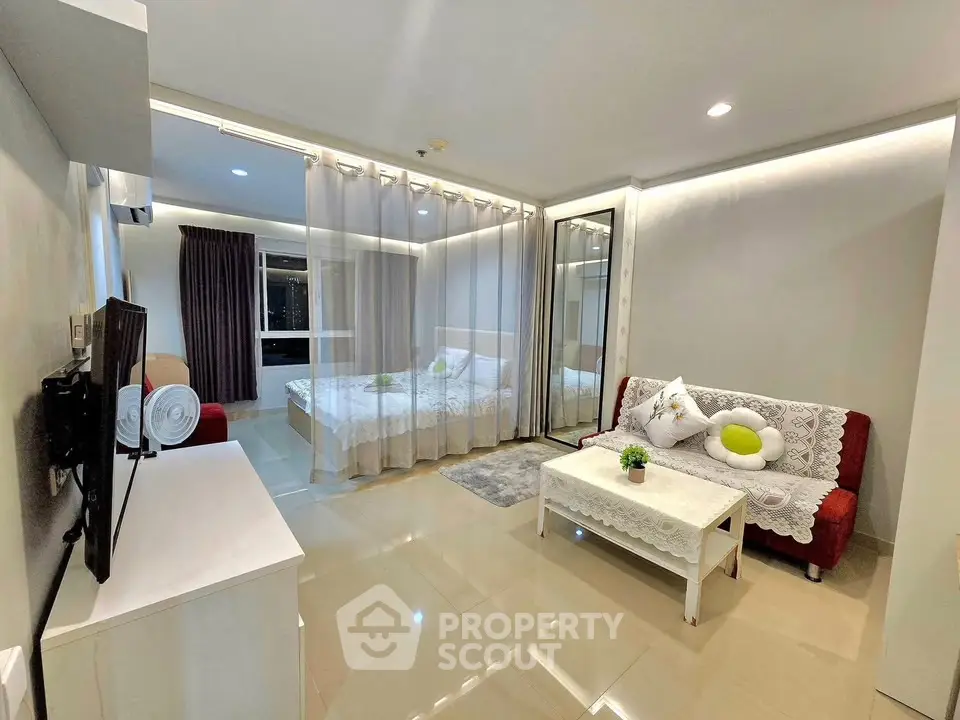 Modern open-plan living room with cozy seating and elegant bedroom divider