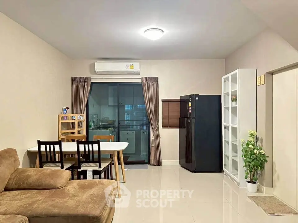 Modern living room with dining area and kitchen view, featuring sleek furniture and neutral tones.