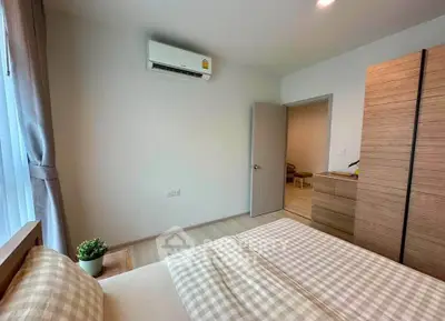 Cozy bedroom with modern decor and natural light, featuring a comfortable bed and stylish wooden wardrobe.
