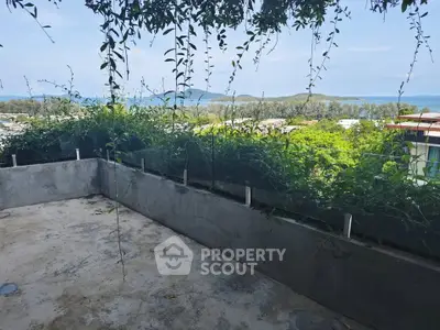 Stunning balcony with lush greenery and panoramic ocean view, perfect for relaxation and enjoying nature.
