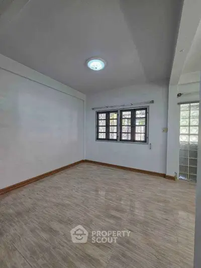 Spacious empty room with large windows and wooden flooring, perfect for customization.