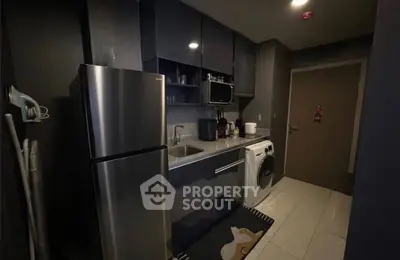 Modern kitchen with sleek appliances and washing machine in compact layout