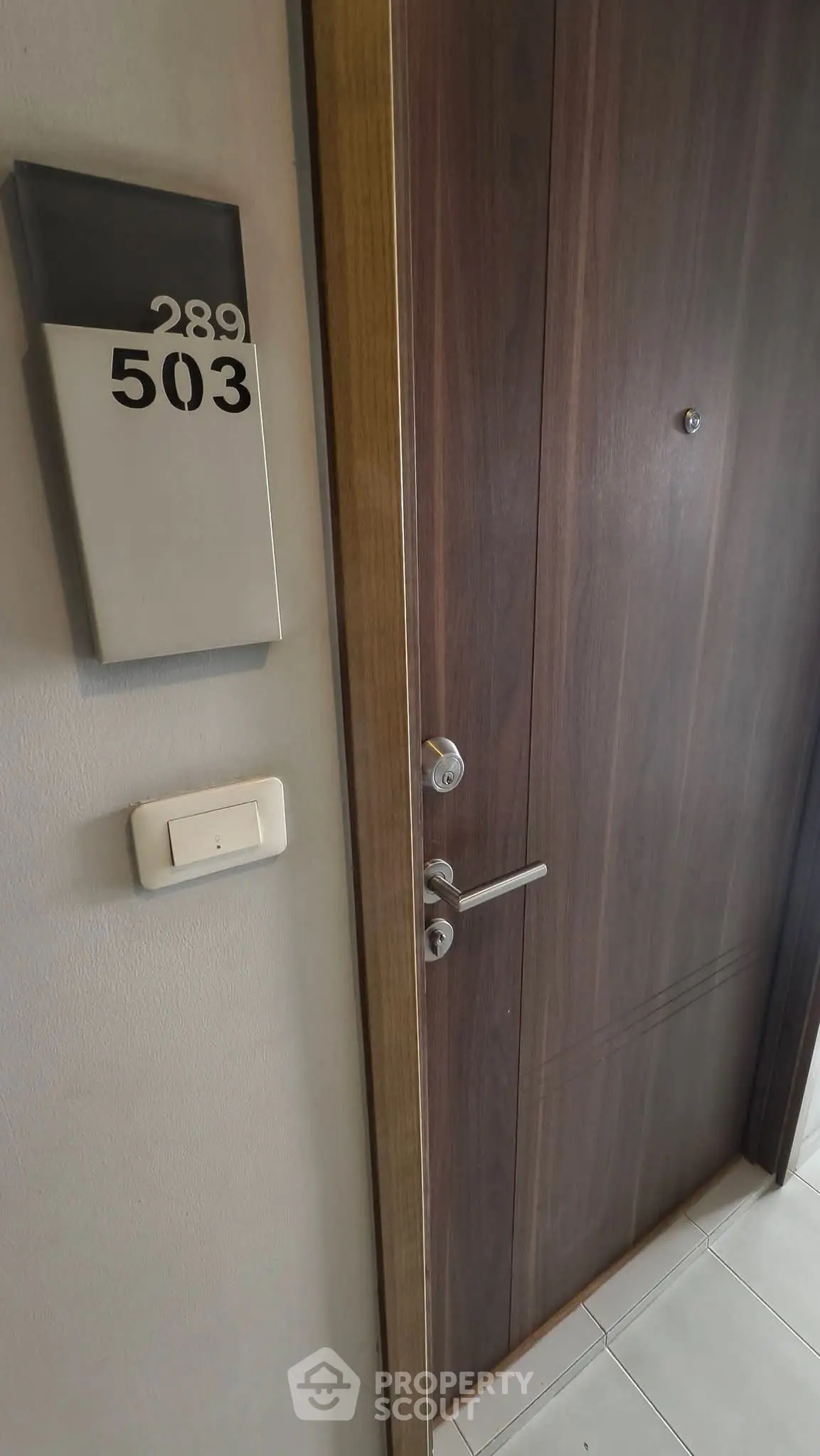 Modern apartment entrance with sleek wooden door and room number 503 displayed.