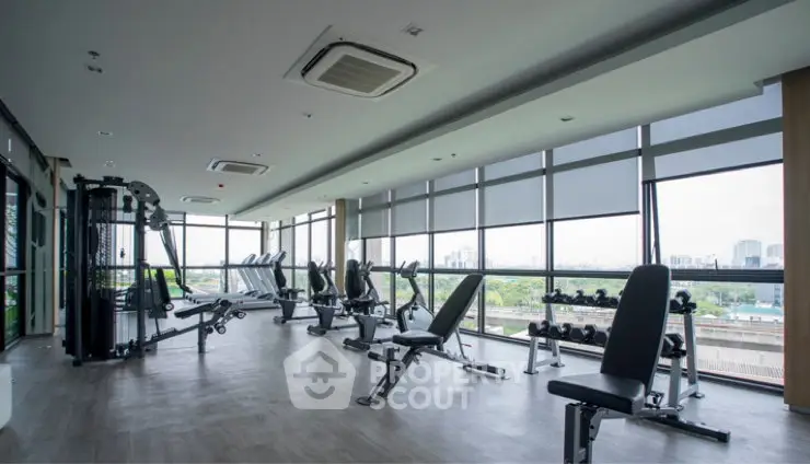 Spacious modern gym with panoramic city views and state-of-the-art fitness equipment.
