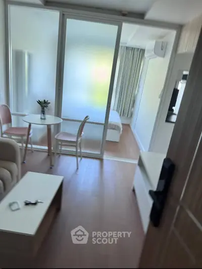 Modern apartment interior with cozy living area and bedroom separated by glass partition.